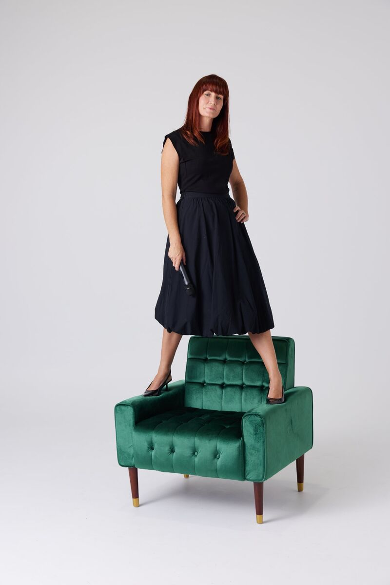 Krystal Brown standing on a green velvet couch, laughing