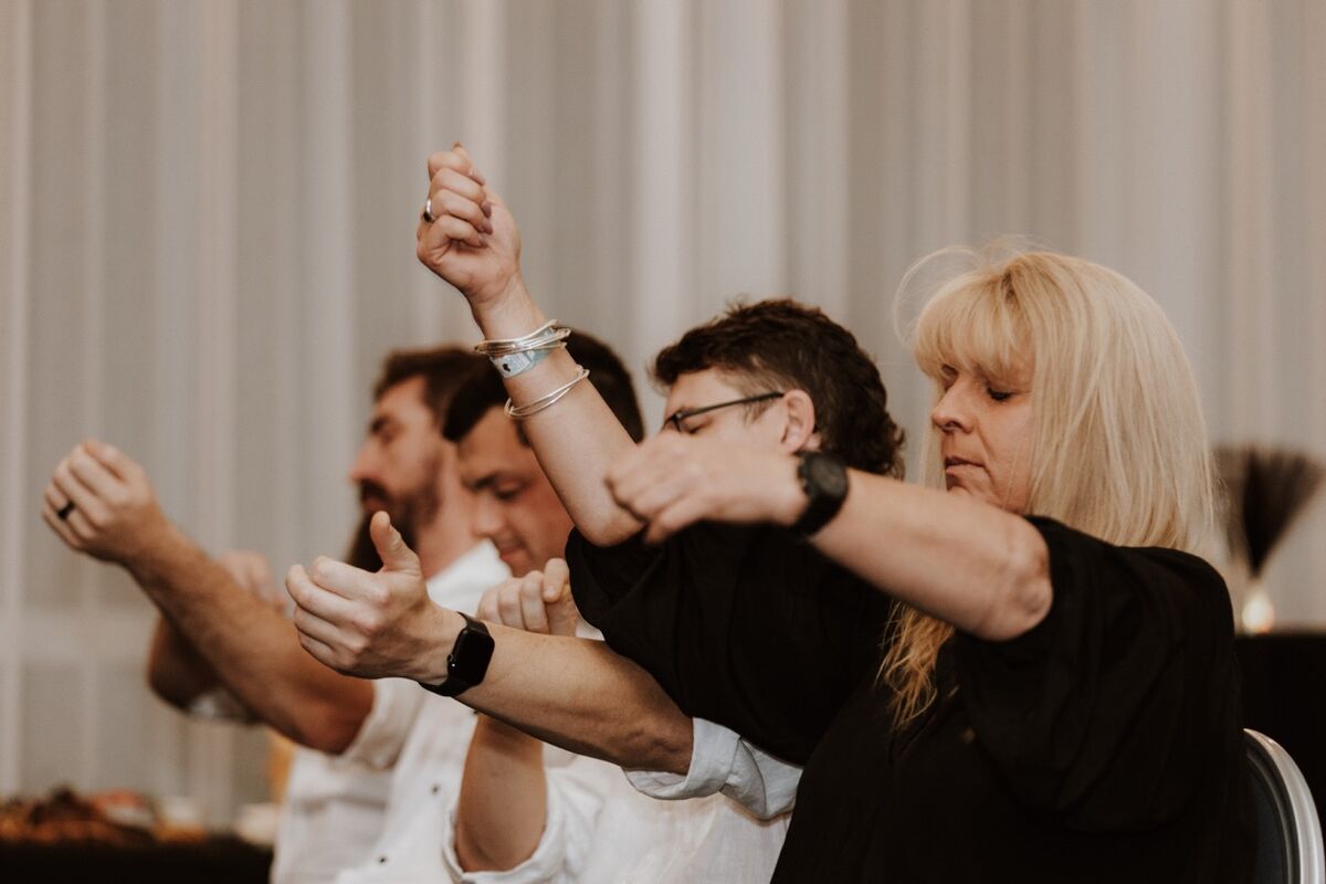 Audience volunteers in trance, arms raised